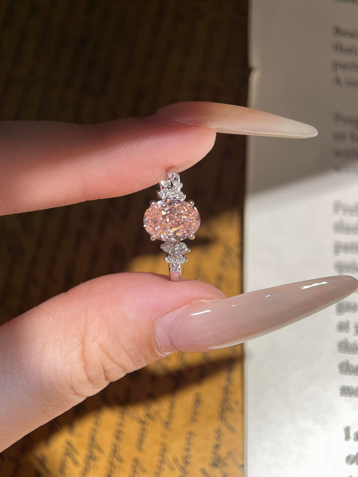 oval pink moissanite engagement ring with sparkling floral side stones.