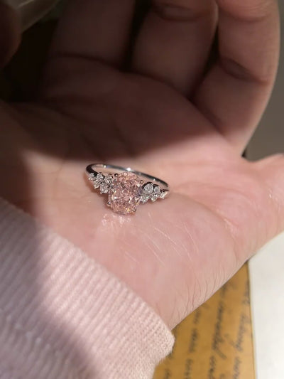 oval pink moissanite engagement ring with sparkling floral side stones.